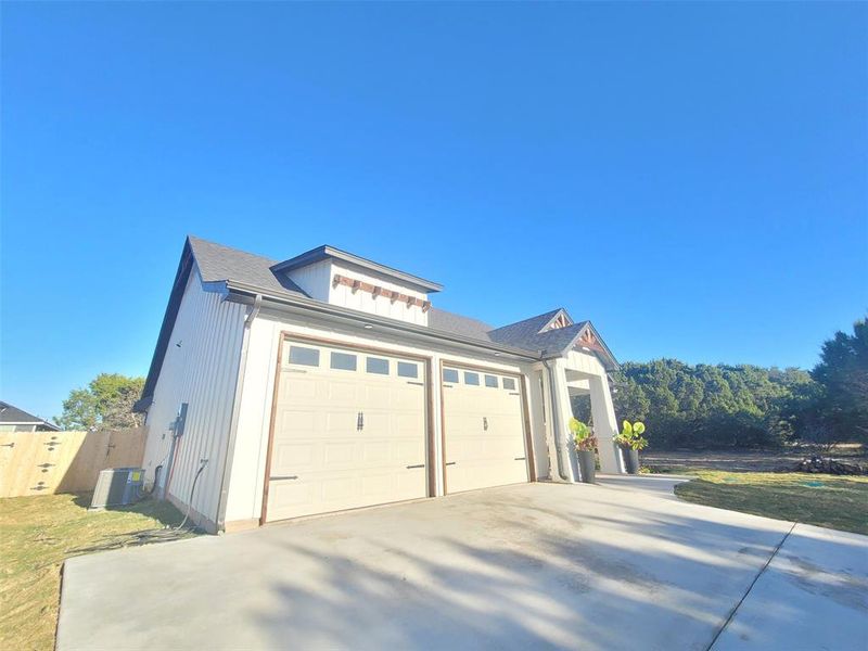 Oversized driveway for larger vehicles and double door garage with widow panels. Side view of structure of house and front porch. Oversized driveway for larger vehicles and double door garage with widow panels. Side view of structure of house and front porch.