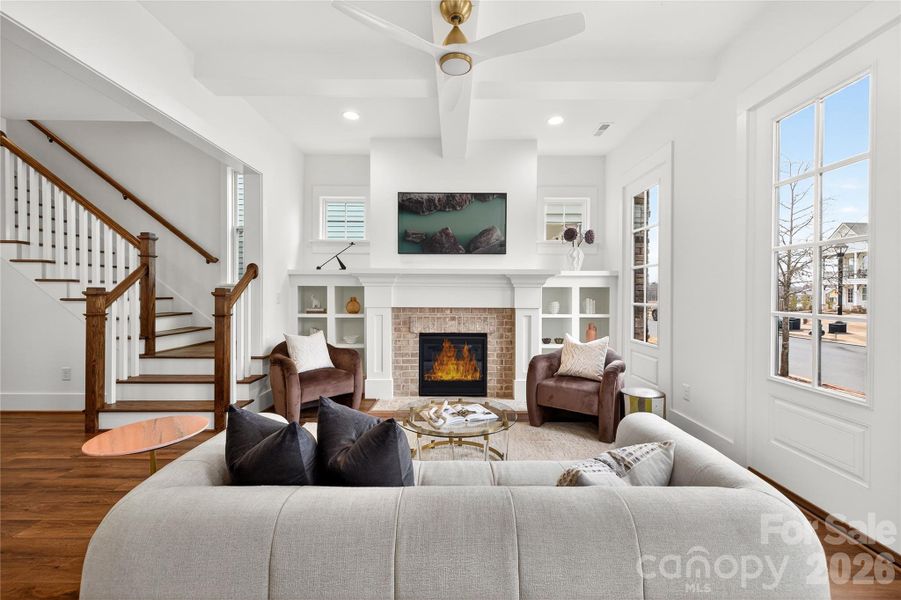 This family room is filled with natural light and showcases ceiling beams and built-in's surrounding a brick fireplace.