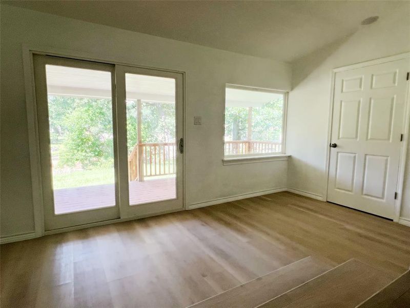 Room featuring wood-finish flooring, a sliding glass door leading to an outdoor deck, and a single window