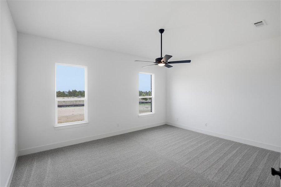 Carpeted spare room with a ceiling fan and baseboards