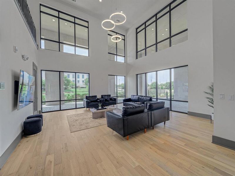 Living room with plenty of natural light, light wood-type flooring, recessed lighting, and a towering ceiling