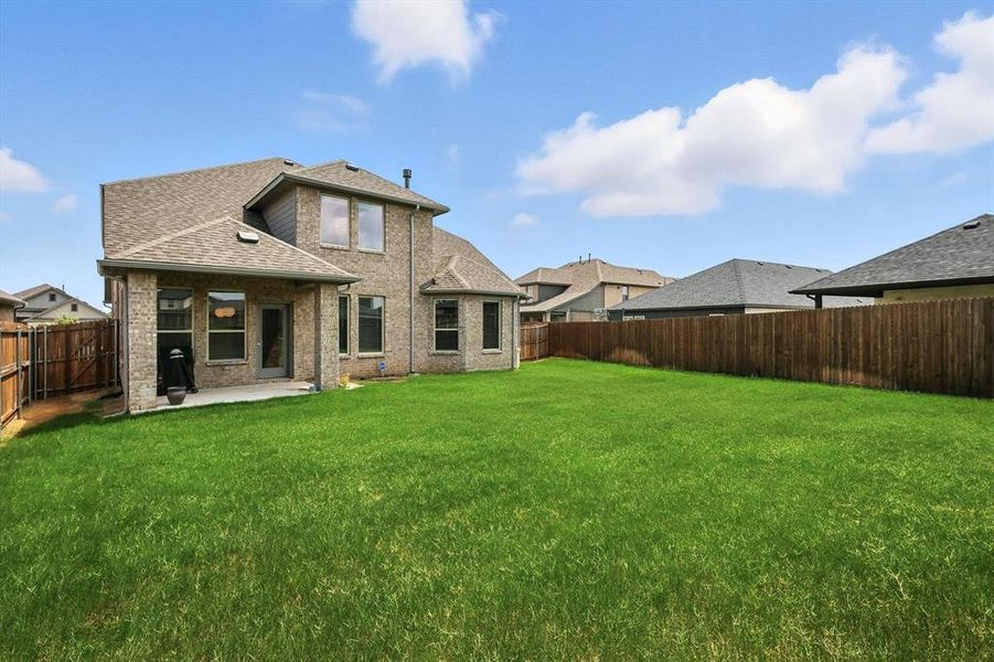 Back of home showcasing the covered patio and large yard.