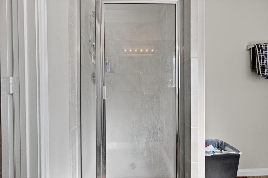 Compact bathroom featuring a tiled walk-in shower with a glass door.