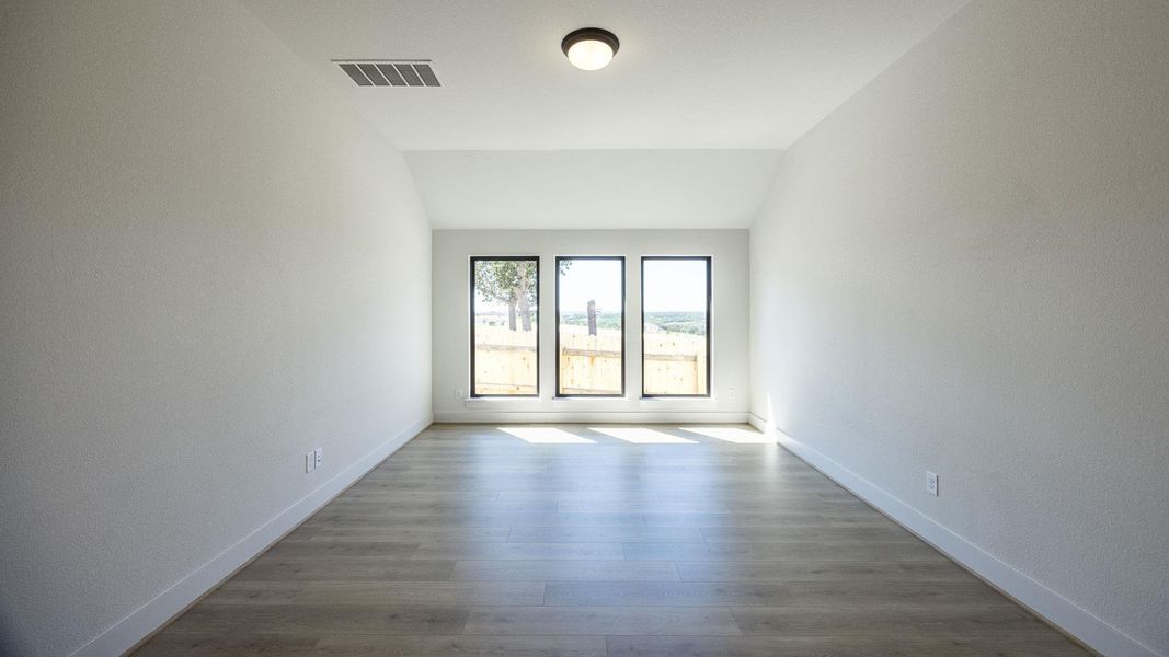 Unfurnished room featuring wood finished floors and vaulted ceiling Unfurnished room featuring wood finished floors and vaulted ceiling