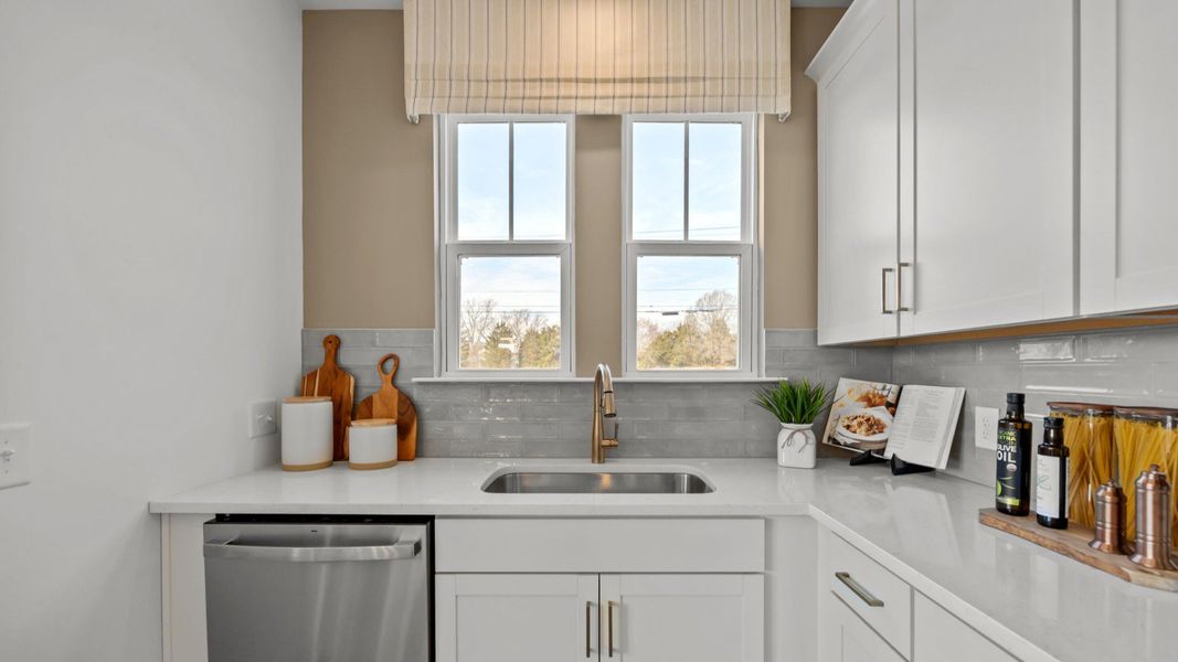 The Rochester Plan by DRB homes kitchen with white cabinets, silver appliances and gold features in Charlotte, NC.