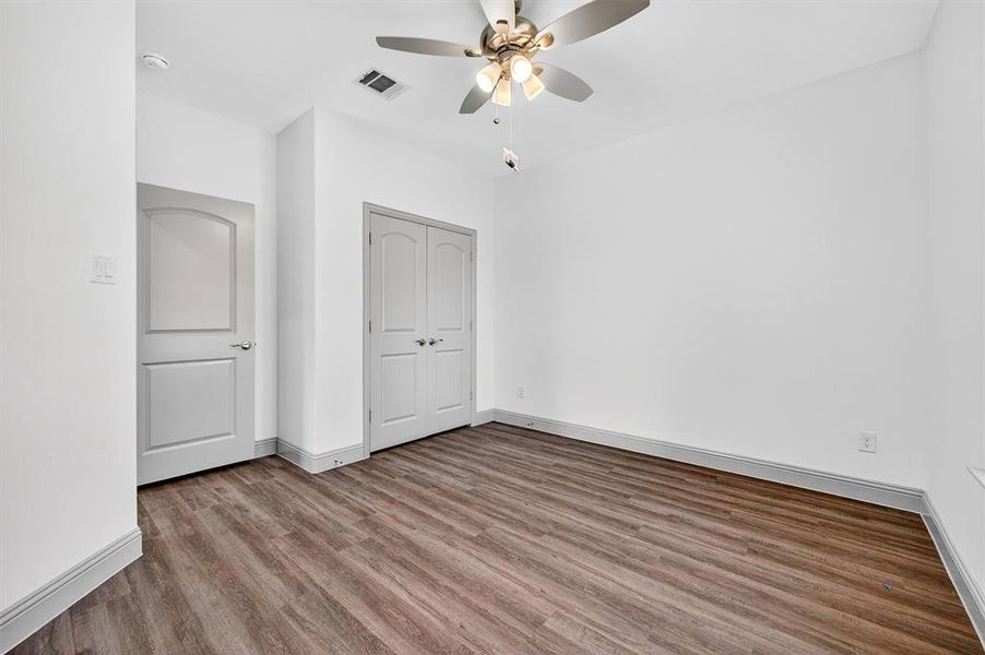 Unfurnished bedroom featuring wood finished floors, a closet, and a ceiling fan