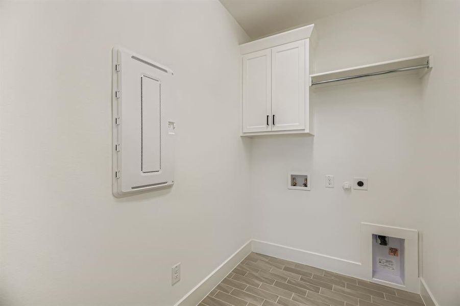 Laundry room featuring hookup for a washing machine, cabinet space, electric panel, electric dryer hookup, and wood tiled floors