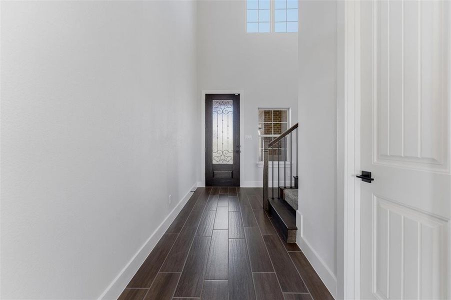 Foyer entrance featuring wood tiled floors, a high ceiling, and stairway