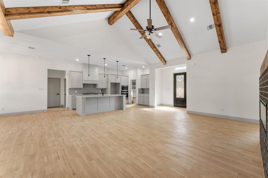 Unfurnished living room featuring high vaulted ceiling, light wood-style flooring, recessed lighting, beamed ceiling, and a ceiling fan