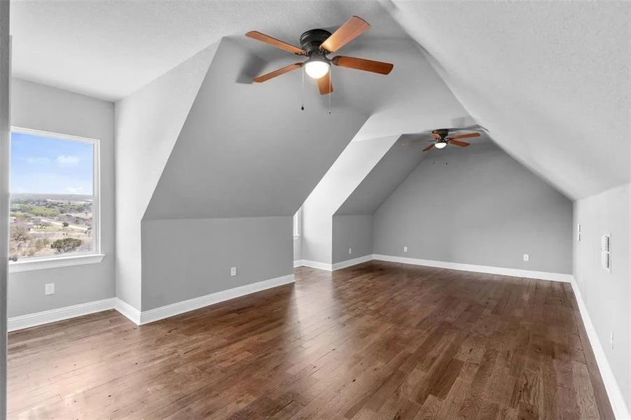 Additional living space featuring a ceiling fan, dark wood-type flooring, a textured ceiling, and vaulted ceiling