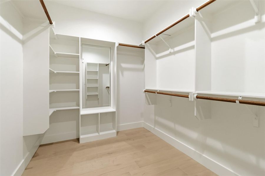 Primary closet with built-in shelving and  full-length mirror