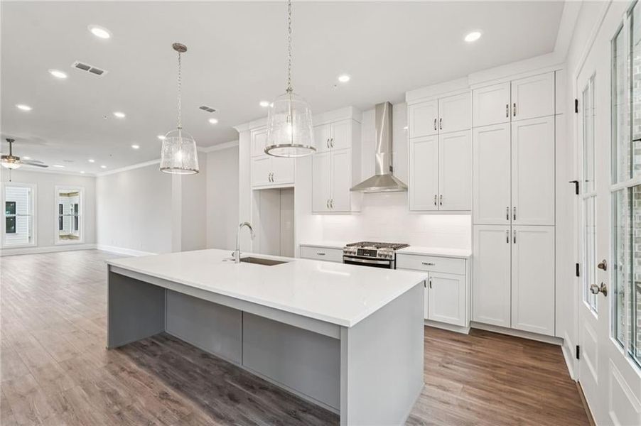 Kitchen featuring pendant lighting, white cabinets, light wood-style floors, stainless steel range with gas stovetop, and crown molding