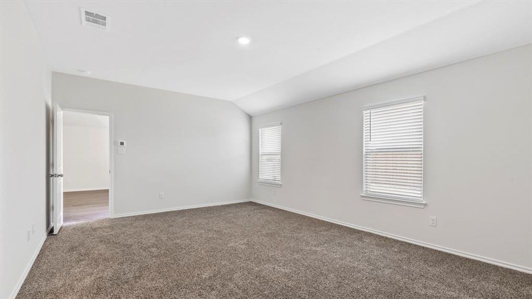 Empty room with dark colored carpet and lofted ceiling