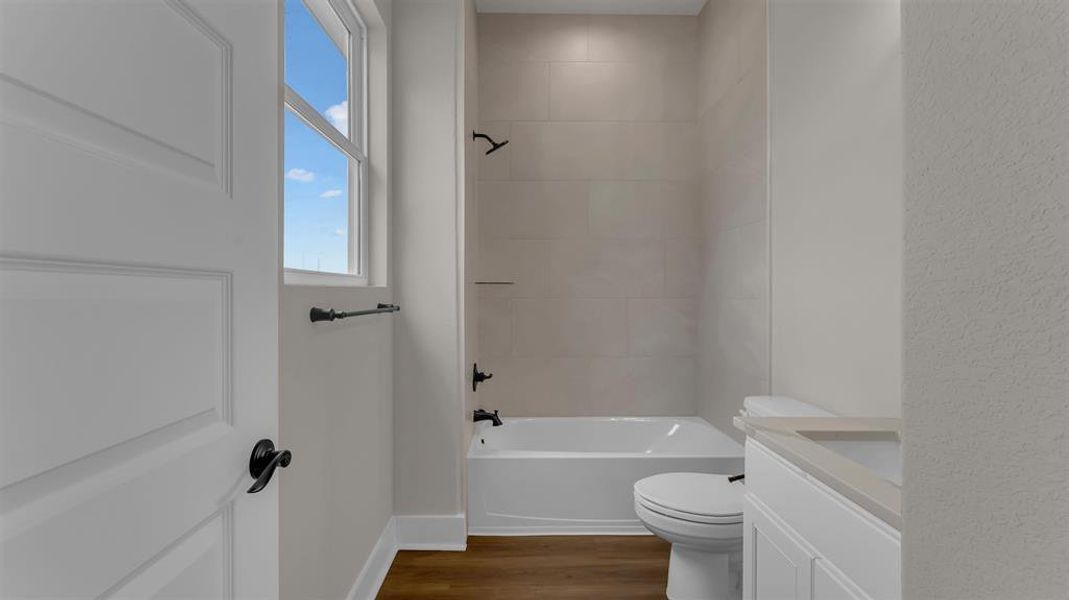 A modern bathroom features clean-lined wall tiles, wood-look flooring, and a classic white tub. A modern bathroom features clean-lined wall tiles, wood-look flooring, and a classic white tub.
