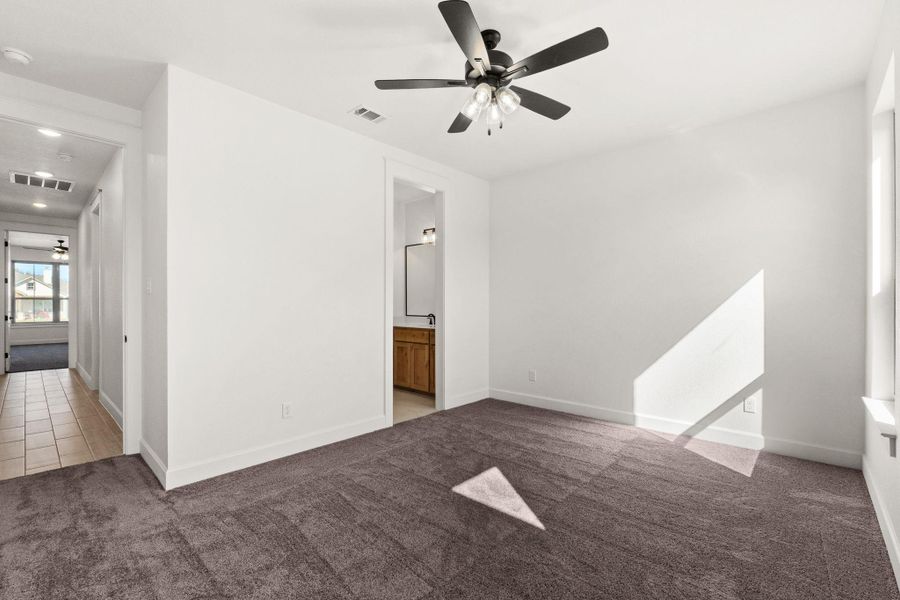 Spare room featuring dark colored carpet, a ceiling fan, and dark tile patterned flooring