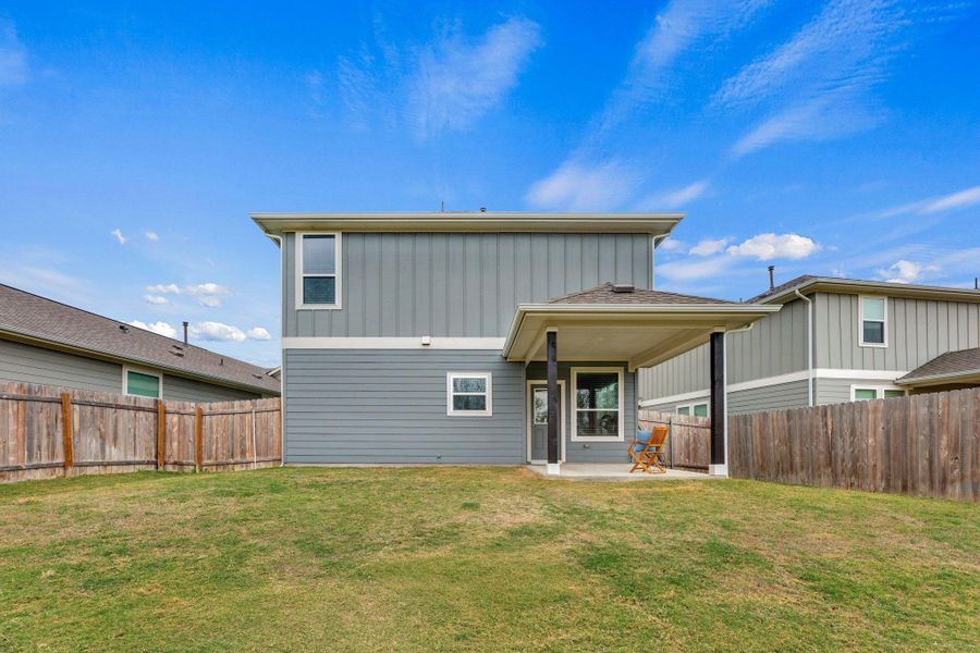 Rear view of property featuring a patio, a fenced backyard, and board and batten siding