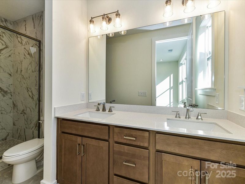 En Suite Primary Bath Featuring Wood-Toned Cabinetry and Dual Vanity.