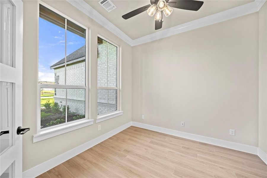 Empty room with ornamental molding and light wood finished floors