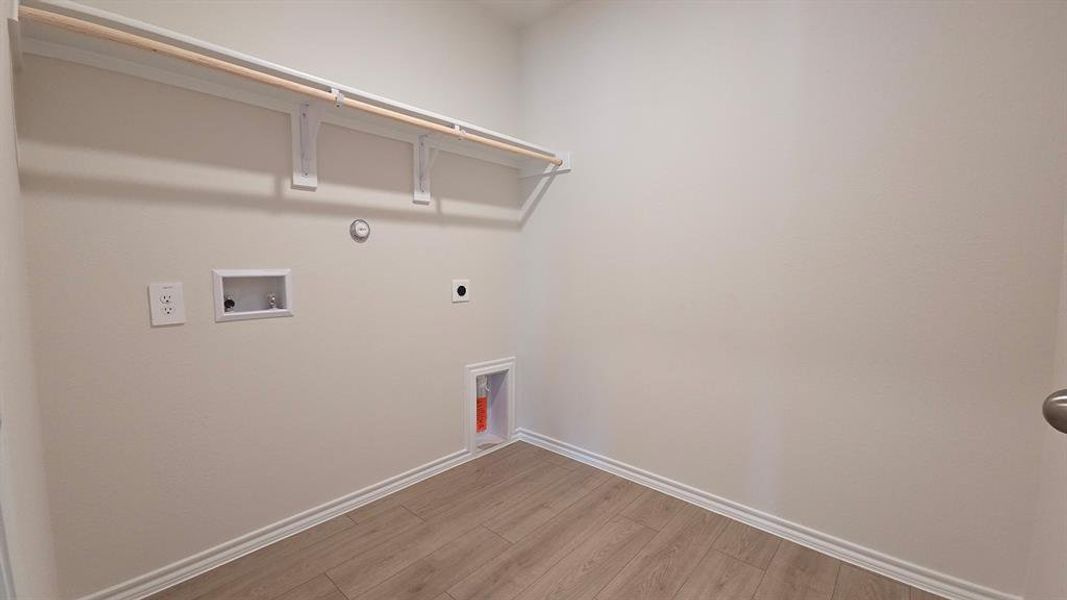 Dedicated laundry space featuring wood-finish flooring, white baseboards, and neutral wall tones