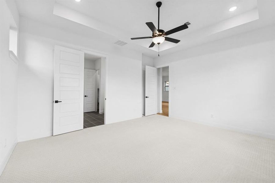 Unfurnished bedroom with a raised ceiling, carpet flooring, a ceiling fan, and recessed lighting Unfurnished bedroom with a raised ceiling, carpet flooring, a ceiling fan, and recessed lighting