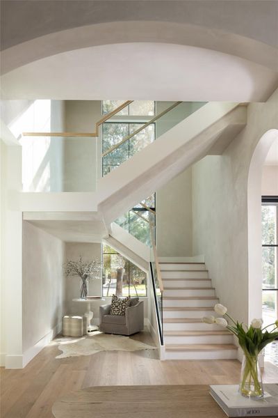 A stunning floating staircase with glass railing, white oak treads, and white oak handrails creates a striking centerpiece upon entry. A stunning floating staircase with glass railing, white oak treads, and white oak handrails creates a striking centerpiece upon entry.