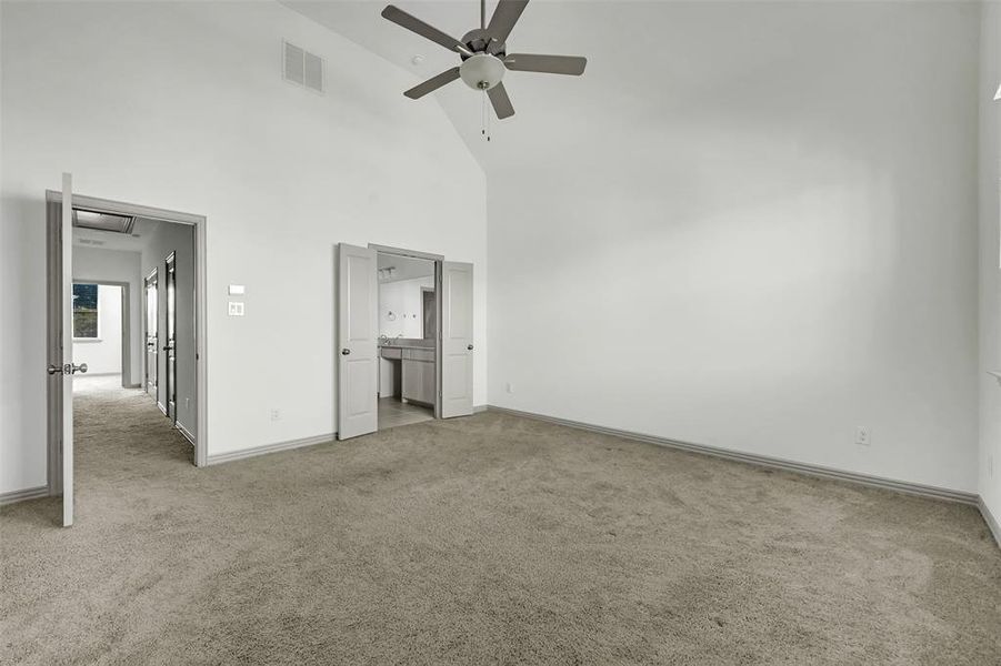 Unfurnished bedroom with high vaulted ceiling, light carpet, ensuite bathroom, and a ceiling fan Unfurnished bedroom with high vaulted ceiling, light carpet, ensuite bathroom, and a ceiling fan
