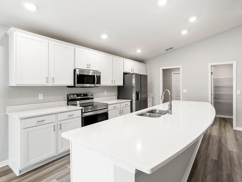 The bright, open kitchen includes a large counter-height island, walk-in pantry, and ample cabinet and counter space - Paisley by Highland Homes