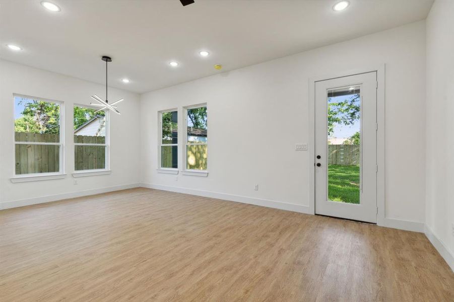 Unfurnished room featuring a healthy amount of sunlight, an inviting chandelier, and light hardwood / wood-style flooring