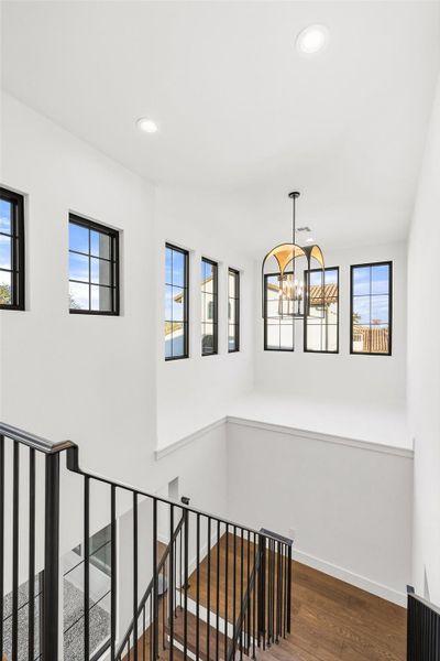 Stairs featuring wood finished floors and hanging lights