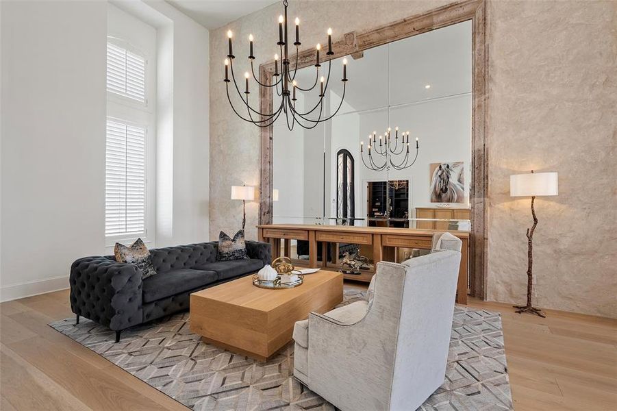 Living room with light wood finished floors, a high ceiling, and a chandelier