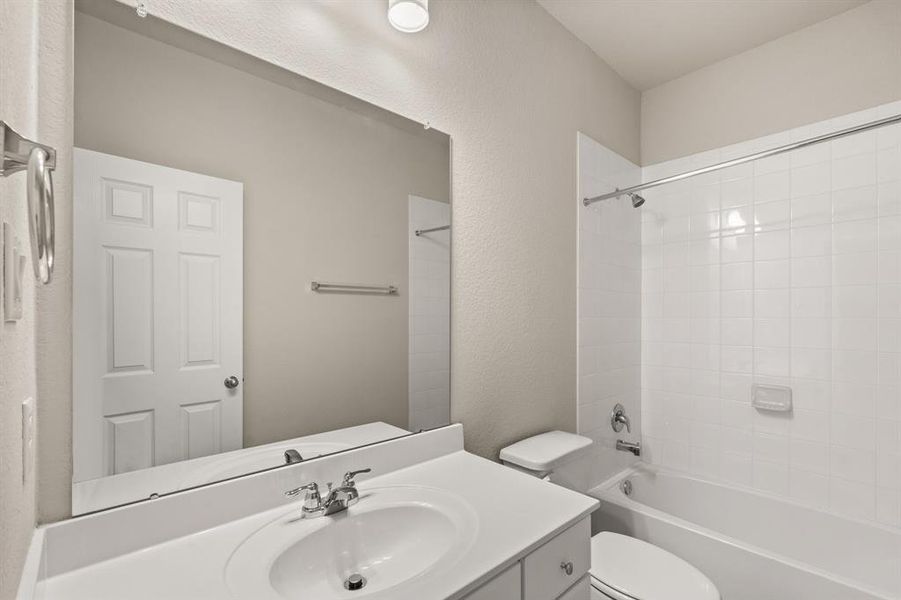 The secondary bath features tile flooring, white cabinetry and light countertops and a shower/tub combo. Perfect for accommodating any visiting family and friends.