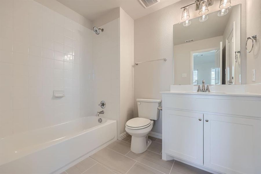 Full bathroom featuring tiled shower / bath, vanity, toilet, and tile patterned flooring