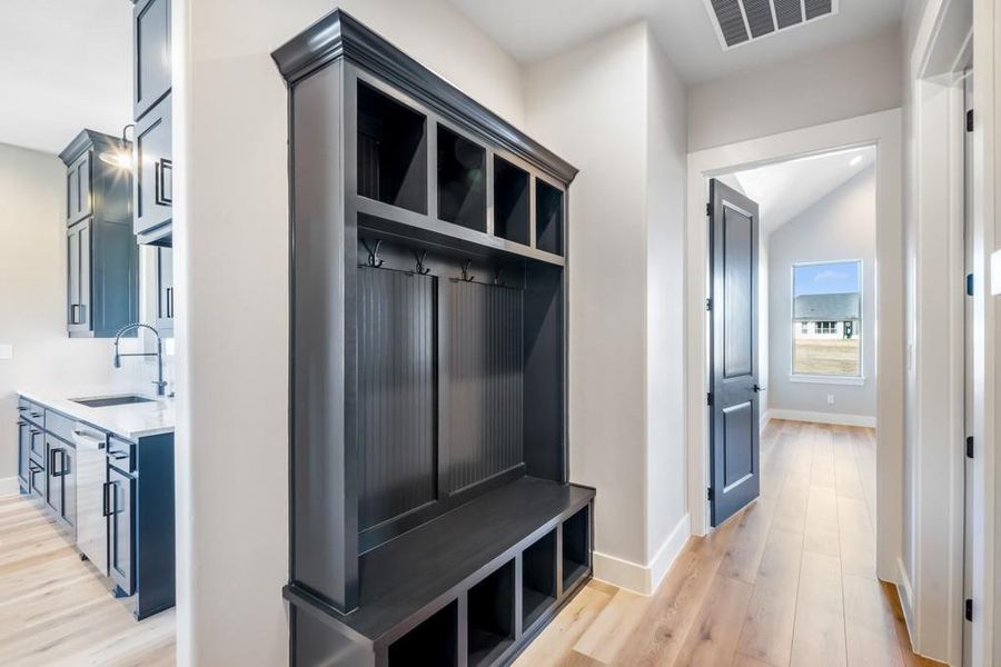 Mudroom featuring lofted ceiling, light wood-type flooring, and sink