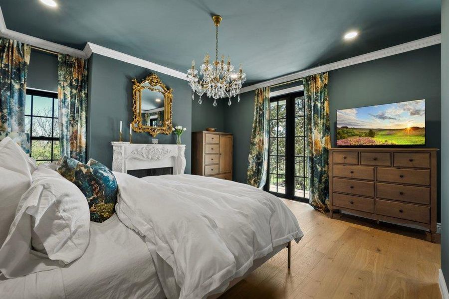 Bedroom featuring light wood-style floors, suspended lighting, and ornamental molding