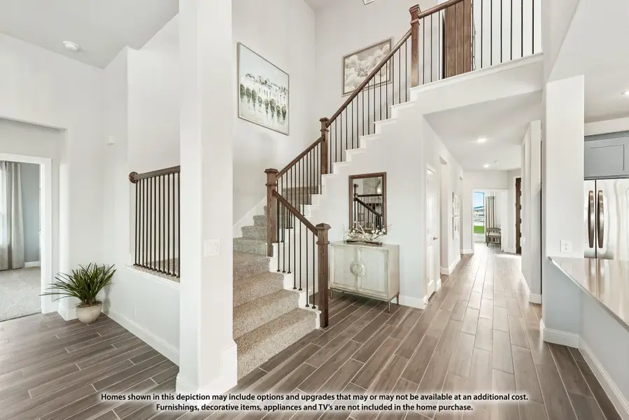 Two-story foyer with carpeted staircase, wood railing, high ceilings, and wood-look tile floors leading to a hallway. Two-story foyer with carpeted staircase, wood railing, high ceilings, and wood-look tile floors leading to a hallway.