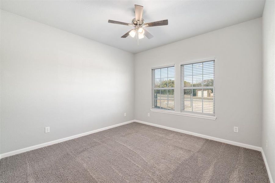 Carpeted spare room featuring ceiling fan