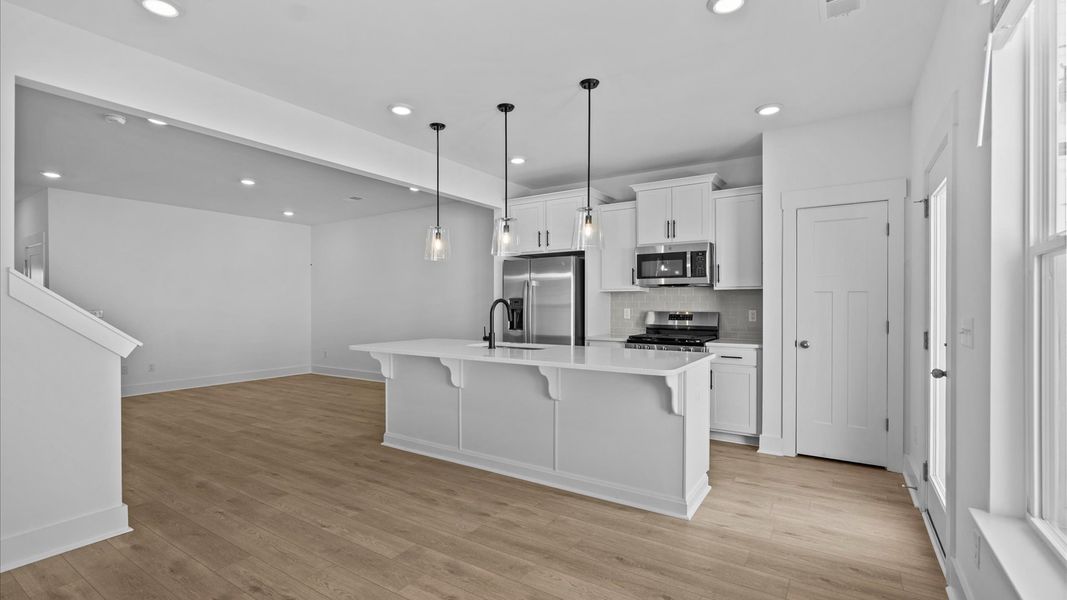 Vibrant and open kitchen centered around a 9-foot island with elegant pendant lighting above Vibrant and open kitchen centered around a 9-foot island with elegant pendant lighting above