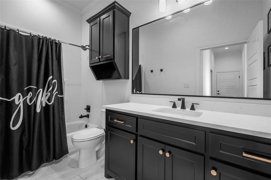 Full bathroom with vanity, shower / tub combo, ornamental molding, and light marble finish floors Full bathroom with vanity, shower / tub combo, ornamental molding, and light marble finish floors