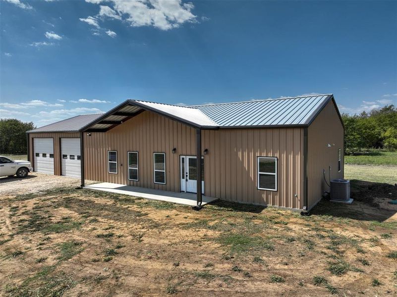 View of front facade featuring a garage, driveway, board and batten siding, a metal roof, and a porch