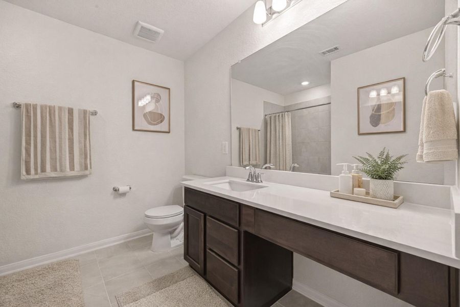 Sleek bathroom with extended vanity, quartz-style countertop, oversized mirror, and modern lighting.