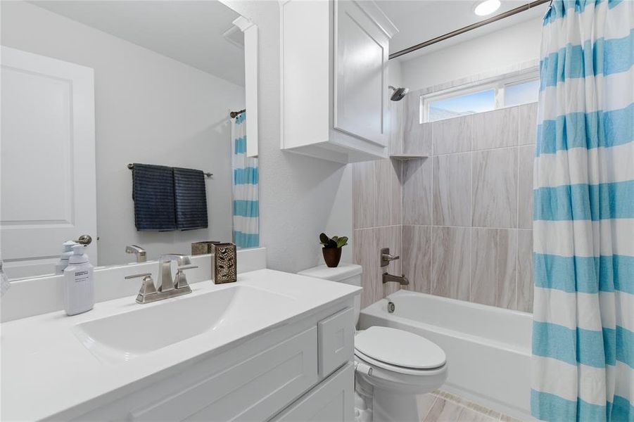 Bathroom featuring a white vanity with integrated sink, brushed nickel faucet, and overhead cabinetry