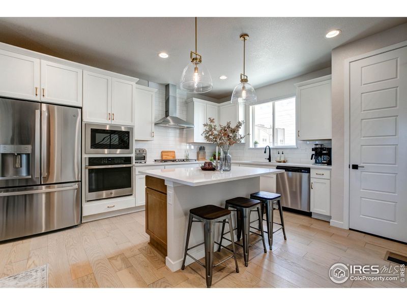 Upgraded kitchen with quartz countertops, gas range with hood, wall oven and microwave.