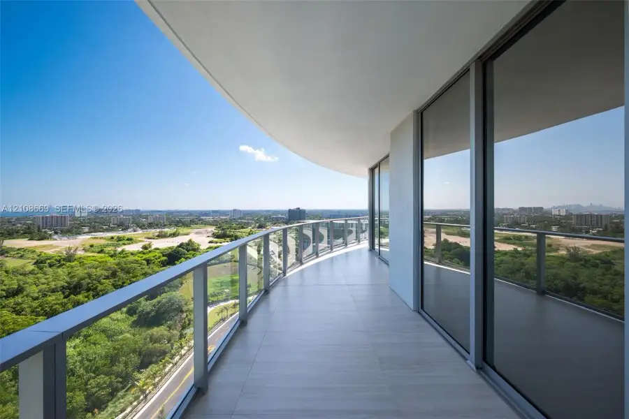 Curved balcony featuring large-format tile flooring, a glass and metal railing, and floor-to-ceiling sliding glass doors