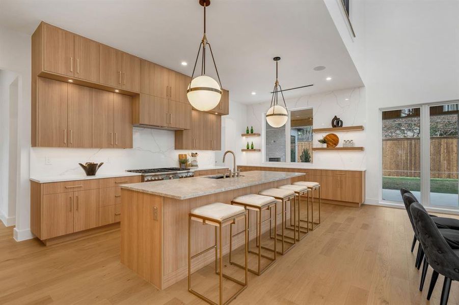 Kitchen with hanging light fixtures, light stone counters, a breakfast bar, modern cabinets, and recessed lighting Kitchen with hanging light fixtures, light stone counters, a breakfast bar, modern cabinets, and recessed lighting