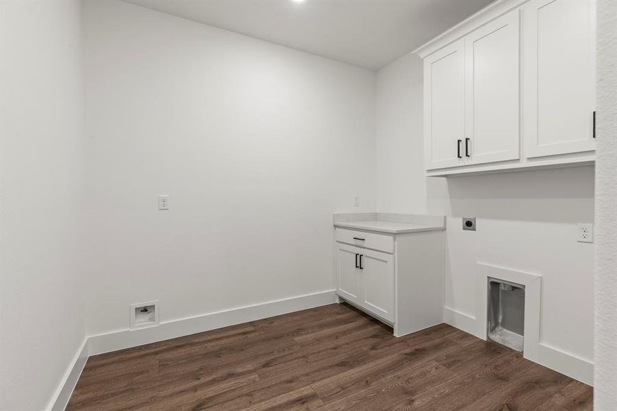 Washroom featuring electric dryer hookup, dark wood-type flooring, and cabinet space