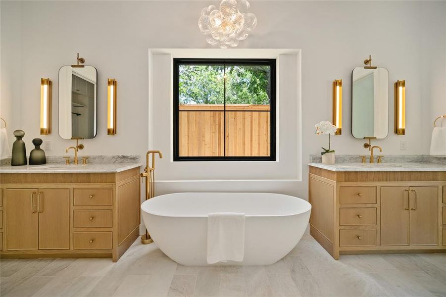 Bathroom with two vanities, a soaking tub, and a chandelier