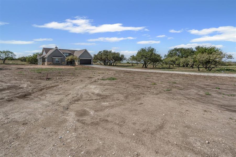 View of yard featuring a rural view, driveway, and a garage