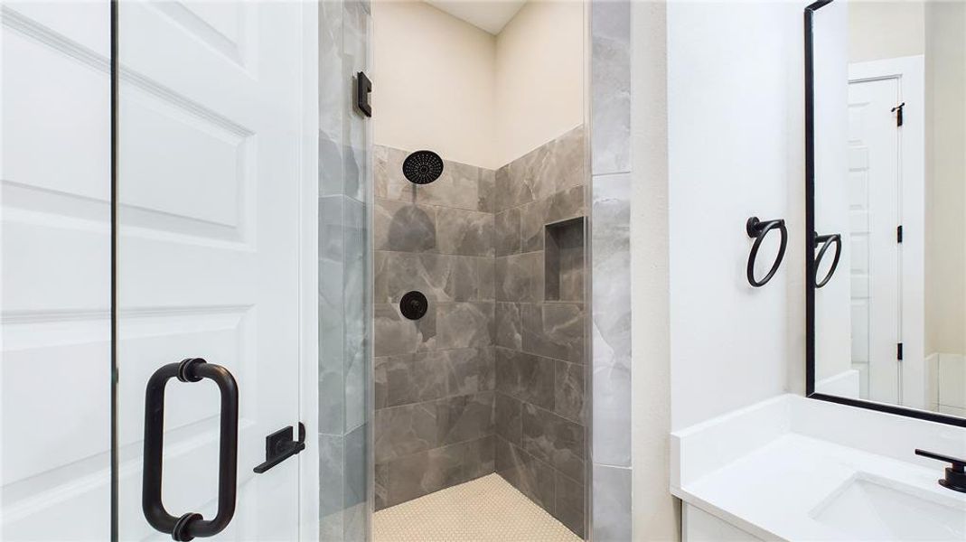 Step into this oversized walk-in shower with sleek glass doors and designer tilework.