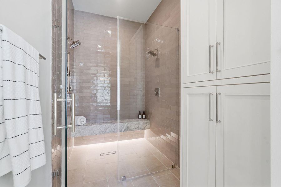 A showpiece walk-in showerwrapped in floor-to-ceiling tile,framed by seamless glass, andfinished with a marble bench andsoft accent lighting—clean,modern, and undeniablyluxurious.