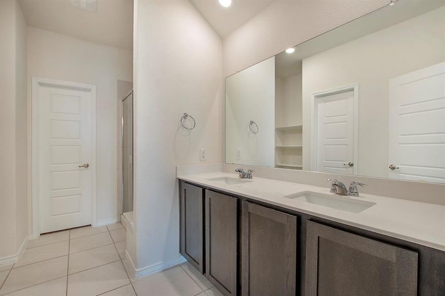 Bathroom with vanity, a shower with shower door, and tile patterned floors